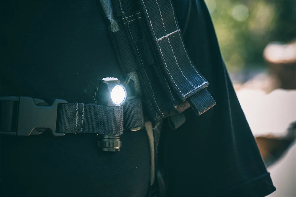 Person wearing a flashlight attached to their belt with a blurred background