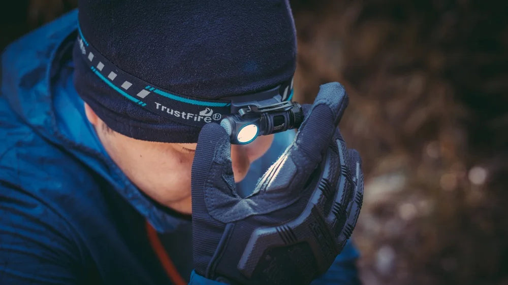 Person wearing a headlamp with a visible brand logo, pointing it towards the camera.