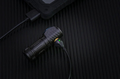 Black flashlight with green light on a textured black surface