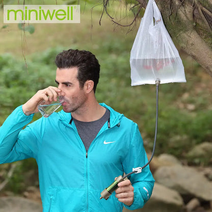 Man drinking water from a portable water filter system in a natural setting.
