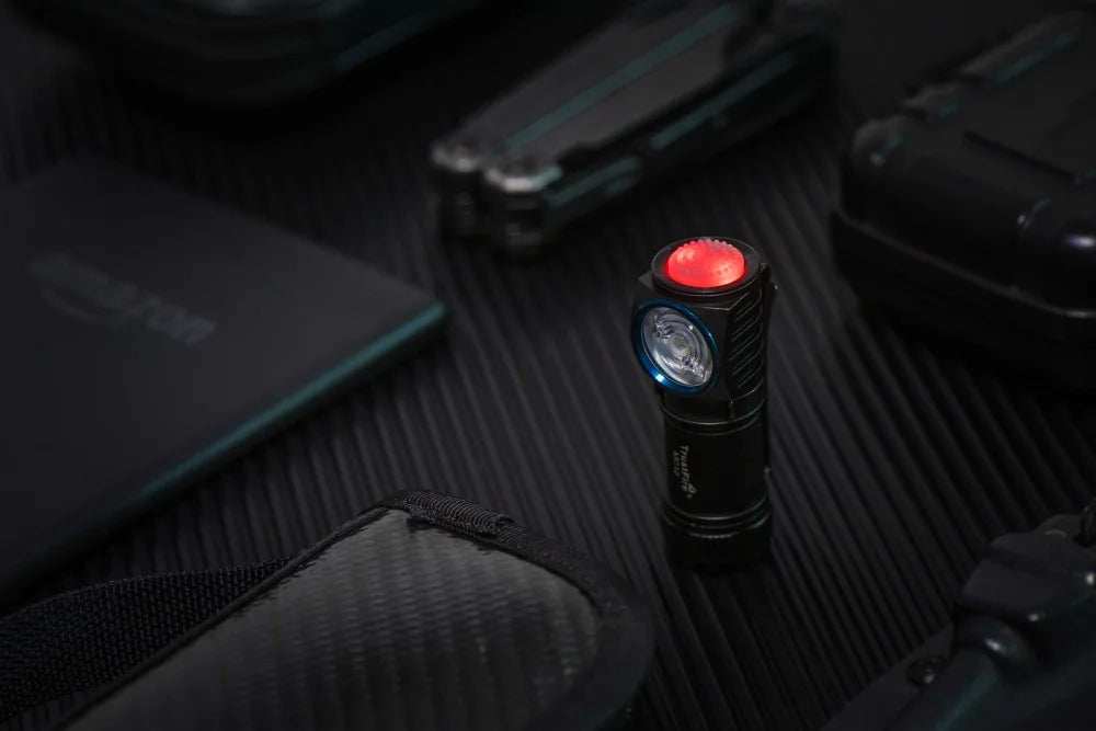Small flashlight with red light on a dark surface