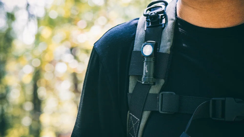 Person wearing a tactical harness with a flashlight in a forest setting