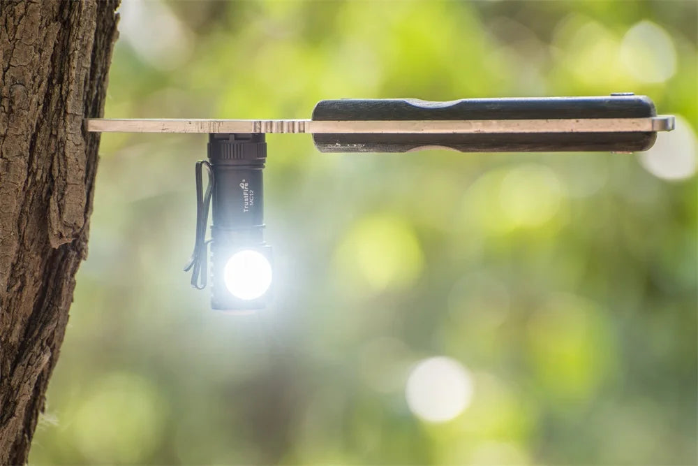Flashlight attached to a tree branch with a blurred green background