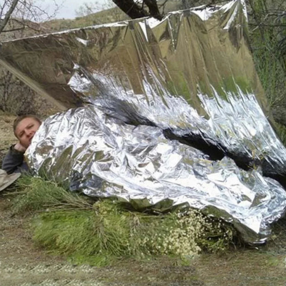 Person wrapped in a large piece of reflective mylar in a natural setting