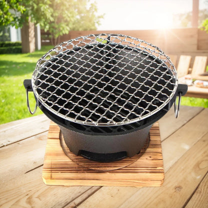 Portable charcoal grill on a wooden surface with a garden background