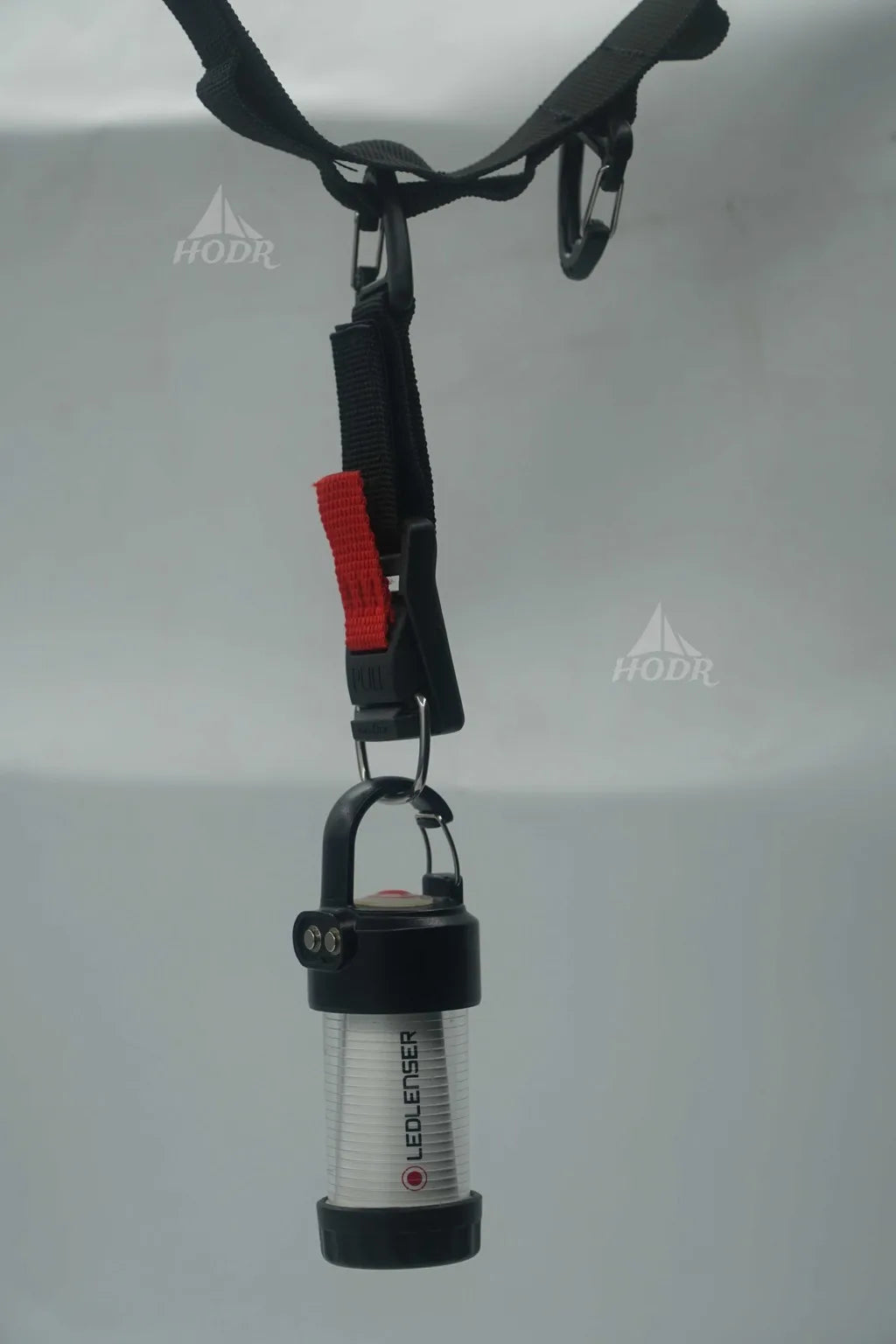 A LECLIEFISH portable lantern with a black and silver body, hanging from a black strap with a red release clip against a light gray background.