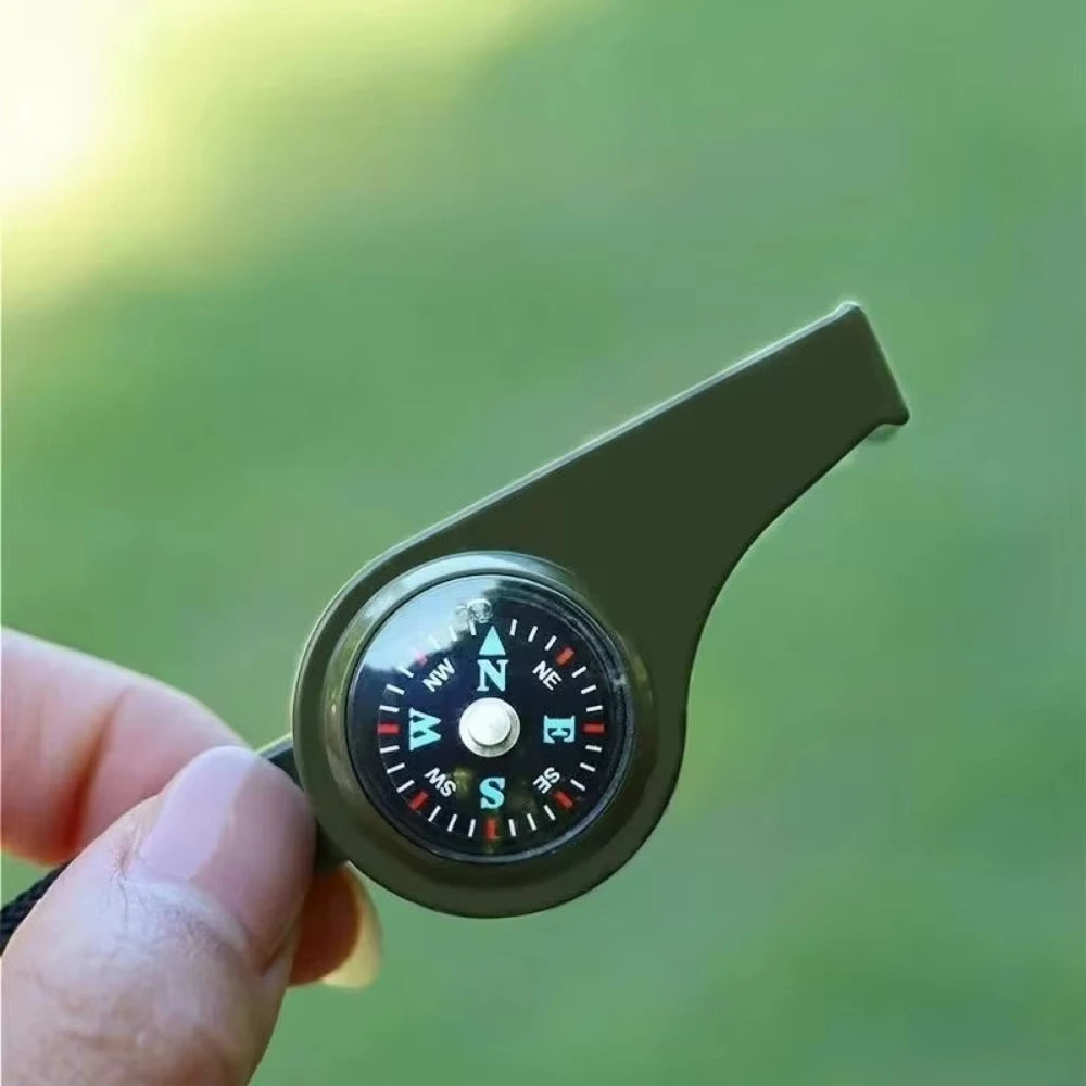 Compass whistle held by a hand with a green blurred background