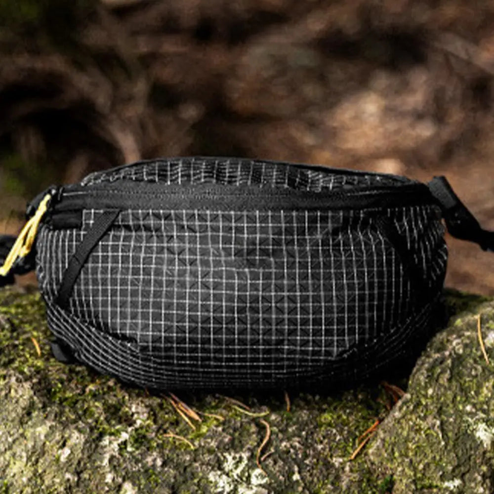 Black grid-patterned bag on a rock with a blurred natural background