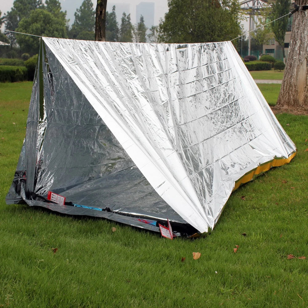 Silver reflective tent on grass with trees in the background