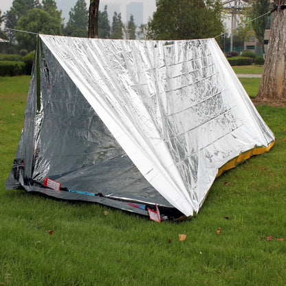 Silver reflective tent on grass with trees in the background