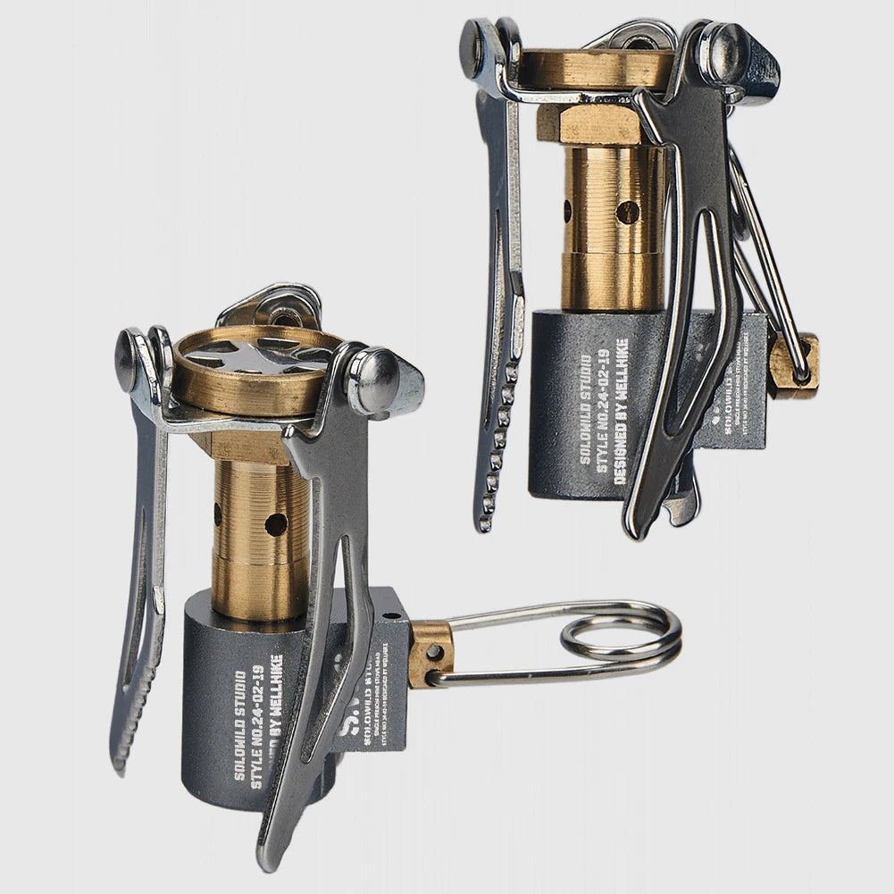 Two portable camping stoves with brass and metal components on a light gray background