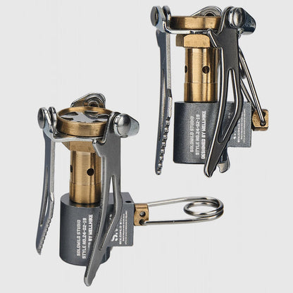 Two portable camping stoves with brass and metal components on a light gray background