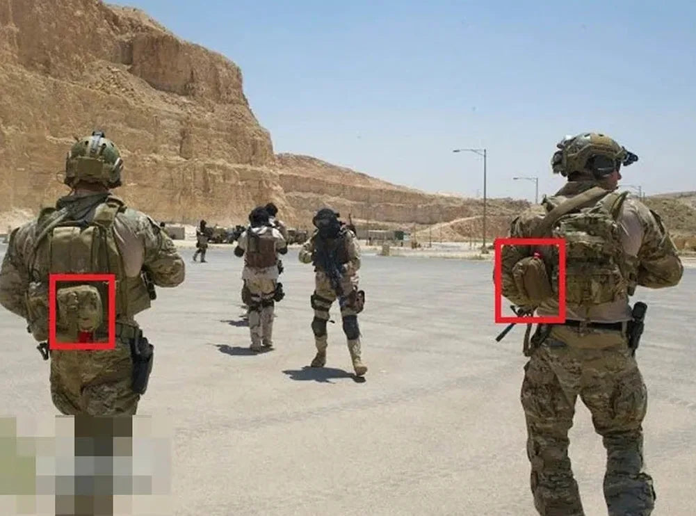 Soldiers in desert camouflage uniforms standing in an outdoor desert setting, with two red boxes highlighting backpack-mounted devices on the left and right soldiers.