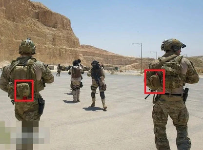 Soldiers in desert camouflage uniforms standing in an outdoor desert setting, with two red boxes highlighting backpack-mounted devices on the left and right soldiers.