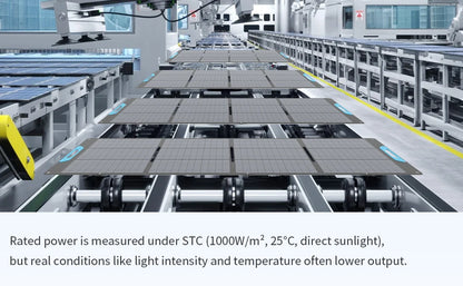 A long row of large rectangular solar panels mounted on a conveyor or assembly line inside a clean industrial facility. The scene is a wide-angle view with machinery, rails, and bright overhead lighting.