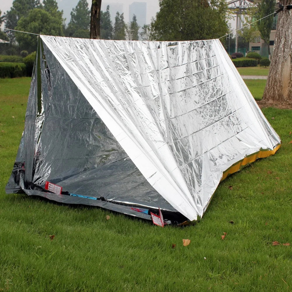 Silver reflective tent on grass with trees in the background