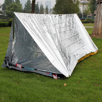 Silver reflective tent on grass with trees in the background