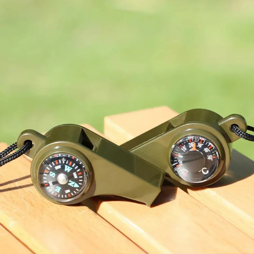 Green whistles with compass and thermometer on a wooden surface with a blurred green background