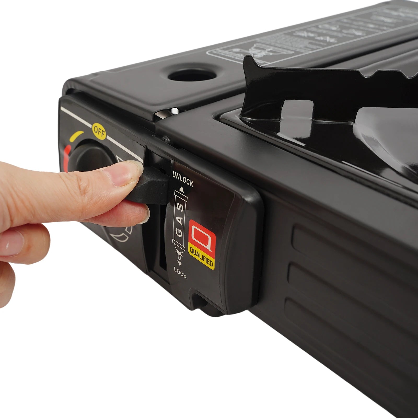 Hand pressing a button on a black portable stove with a white background