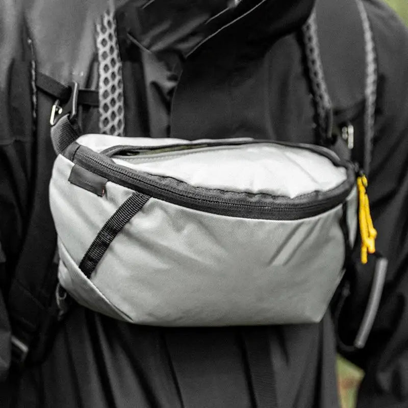 Person wearing a black backpack with a gray waist bag attached