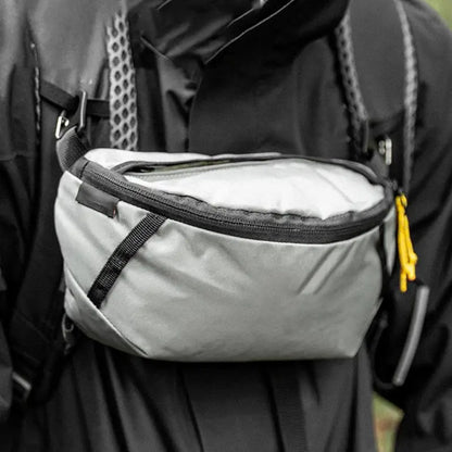 Person wearing a black backpack with a gray waist bag attached