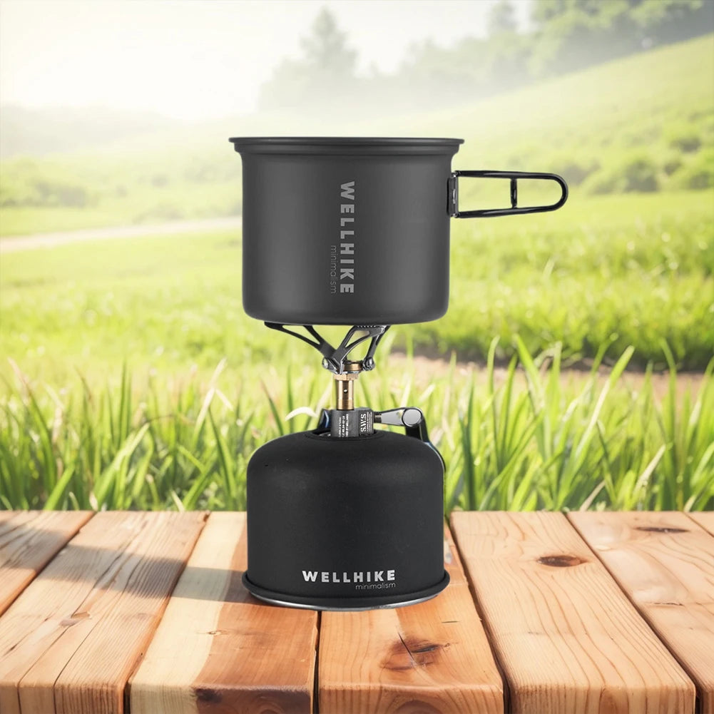 Black camping stove with pot on a wooden surface in a natural setting