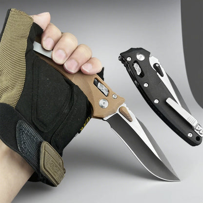 Hand holding a knife with a tactical glove, another knife on a gray background