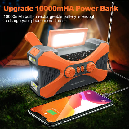 Orange power bank with flashlight and radio, charging a phone, on grass with fire in the background
