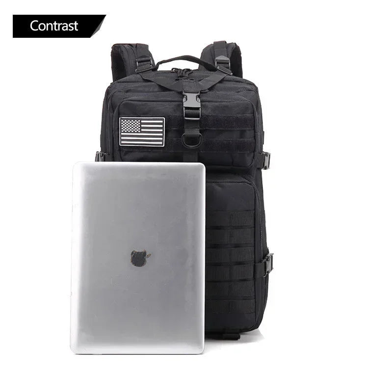 Black tactical backpack with American flag patch next to a silver laptop on a white background