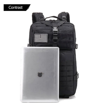 Black tactical backpack with American flag patch next to a silver laptop on a white background
