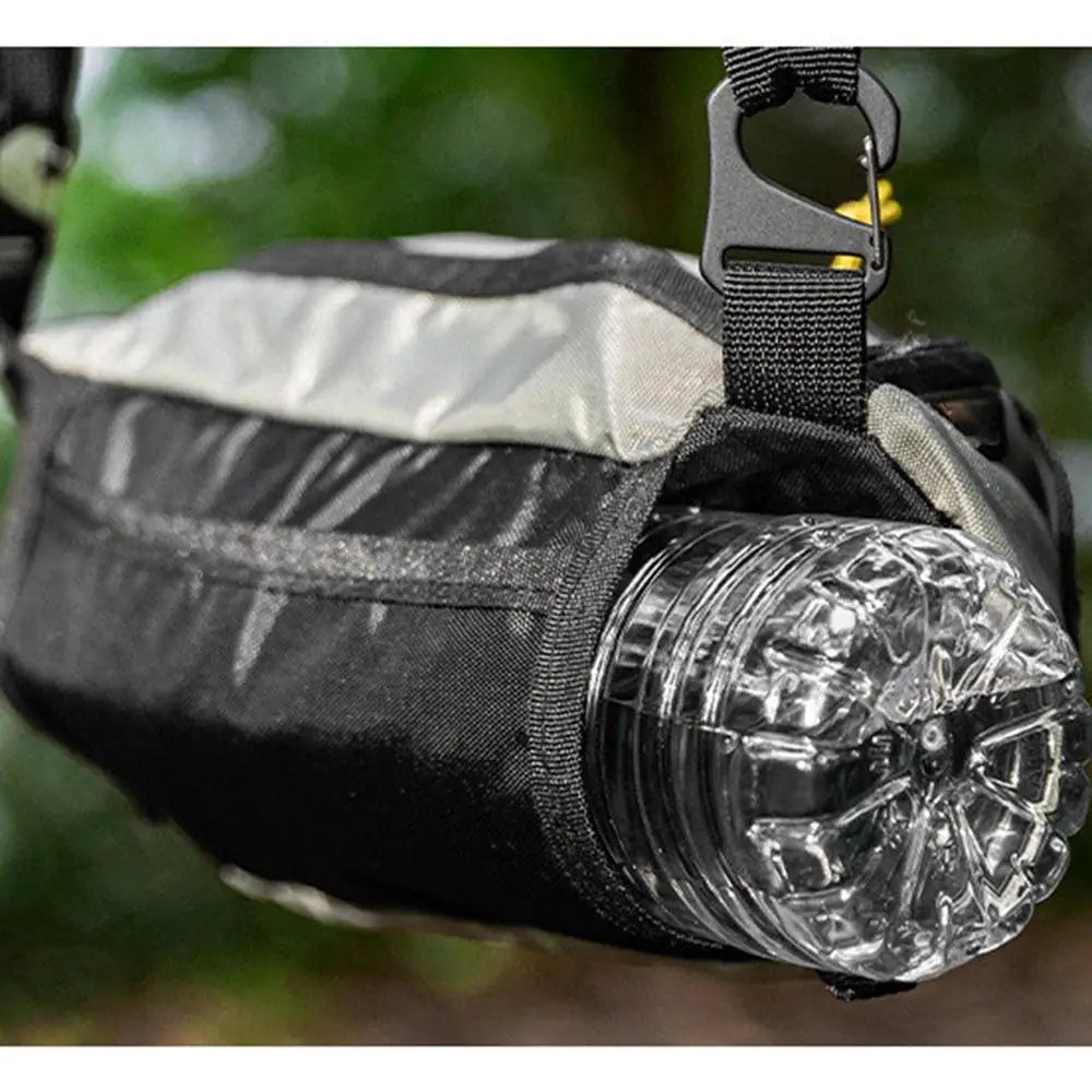 Black bag with a clear water bottle attached, set against a blurred green background