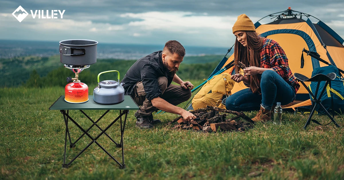 Two people camping outdoors with a Villey stove and tent in the background.