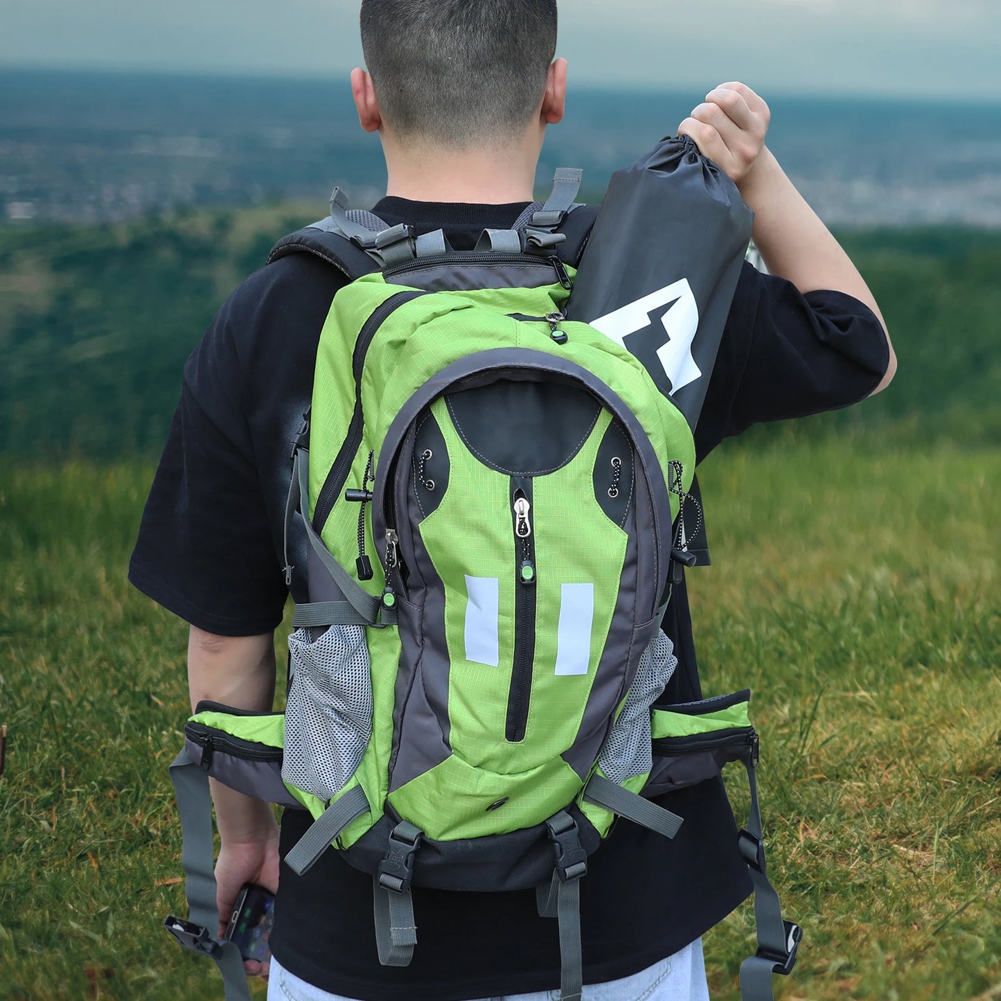 Person wearing a green and gray backpack in a scenic outdoor setting