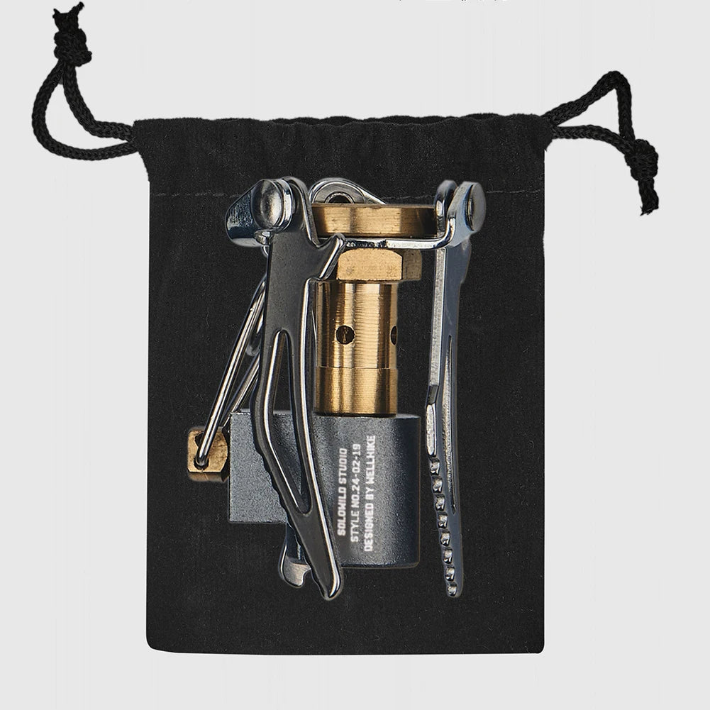 Multitool with brass component and knife on a black drawstring pouch against a light gray background