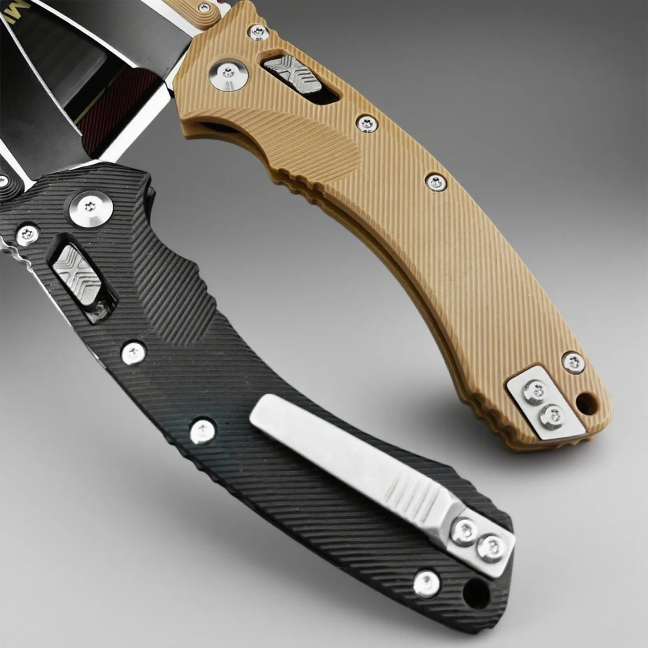 Two folding knives, one with a black handle and the other with a tan handle, on a gray background.