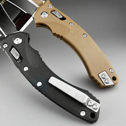 Two folding knives, one with a black handle and the other with a tan handle, on a gray background.